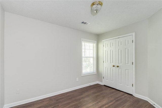 unfurnished bedroom featuring baseboards, a closet, and dark wood-style flooring