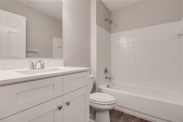 full bath with shower / bathtub combination, a textured ceiling, toilet, and wood finished floors