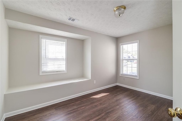 empty room with baseboards, dark wood-type flooring, and visible vents