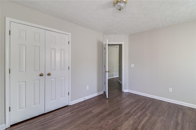 unfurnished bedroom featuring baseboards, wood finished floors, a textured ceiling, and a closet