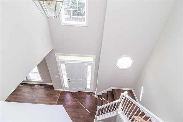 entrance foyer featuring baseboards, wood finished floors, and a towering ceiling