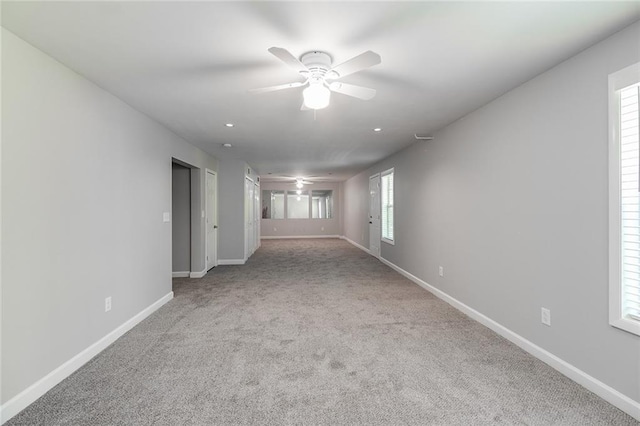 carpeted empty room with baseboards, ceiling fan, and a healthy amount of sunlight