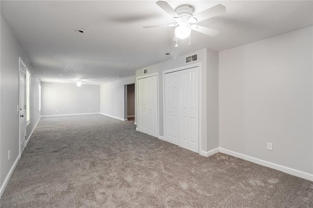 interior space featuring two closets, baseboards, carpet flooring, and visible vents