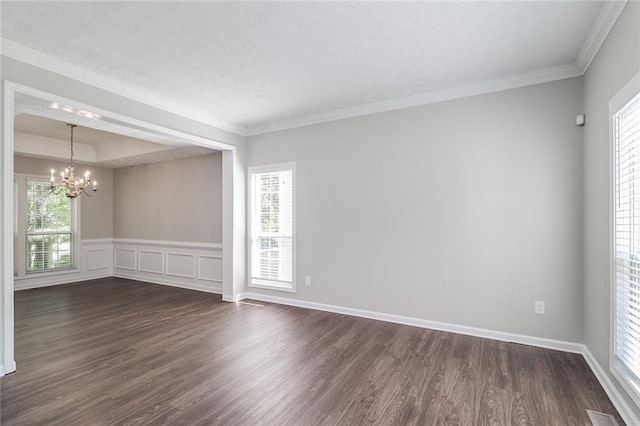 empty room featuring a textured ceiling, crown molding, dark wood-style flooring, and an inviting chandelier