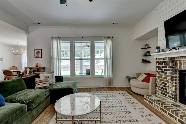 2129 Charmond Dr, Monroe, GA 30656 - living area featuring wood finished floors, ceiling fan, a chandelier, crown molding, and a fireplace