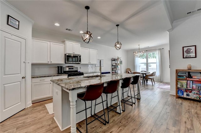2129 Charmond Dr, Monroe, GA 30656 - kitchen featuring appliances with stainless steel finishes, a kitchen breakfast bar, white cabinets, light stone countertops, and recessed lighting