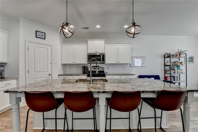 2129 Charmond Dr, Monroe, GA 30656 - kitchen featuring stainless steel appliances, crown molding, white cabinetry, a kitchen island with sink, and recessed lighting