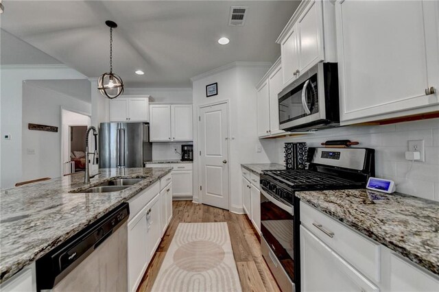 2129 Charmond Dr, Monroe, GA 30656 - kitchen with appliances with stainless steel finishes, crown molding, light wood-style flooring, white cabinetry, and recessed lighting
