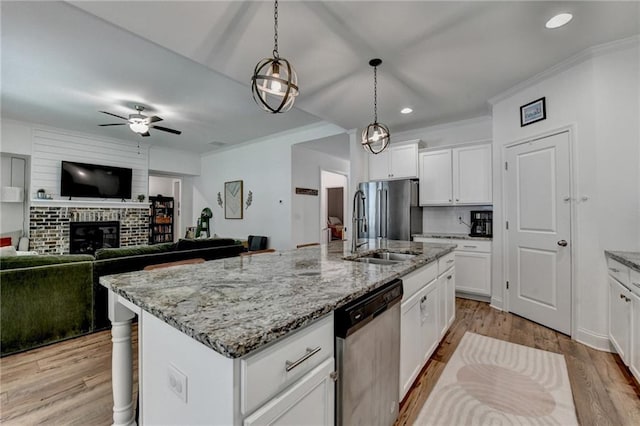 2129 Charmond Dr, Monroe, GA 30656 - kitchen with stainless steel appliances, ceiling fan, a center island with sink, open floor plan, and a fireplace