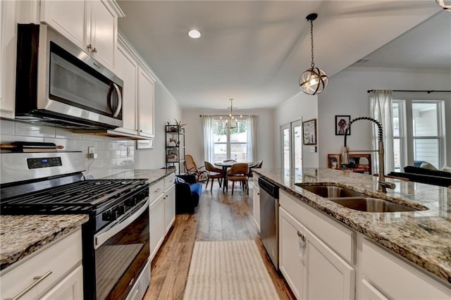 2129 Charmond Dr, Monroe, GA 30656 - kitchen with appliances with stainless steel finishes, light wood-style flooring, decorative backsplash, white cabinetry, and decorative light fixtures