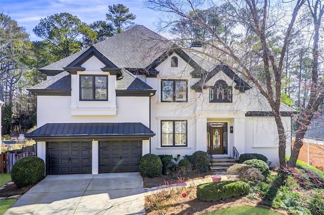 french country inspired facade featuring a shingled roof, concrete driveway, metal roof, an attached garage, and a standing seam roof