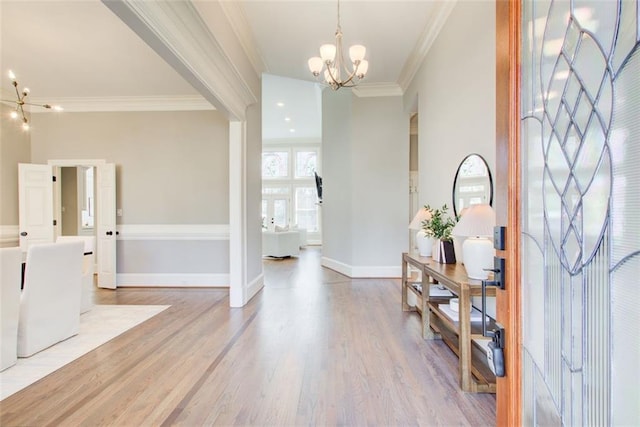 foyer featuring light wood-type flooring, an inviting chandelier, baseboards, and crown molding