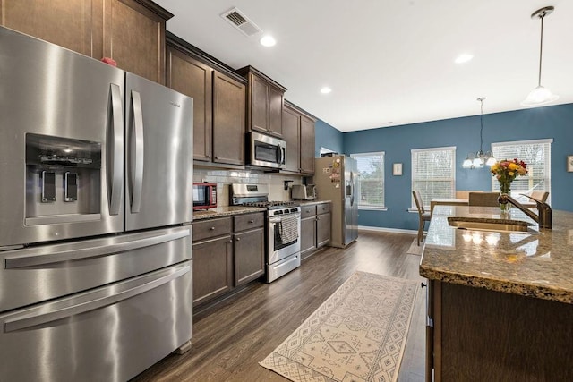 kitchen with tasteful backsplash, visible vents, appliances with stainless steel finishes, a sink, and dark brown cabinets