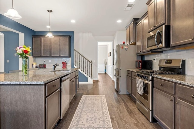 kitchen with light stone counters, stainless steel appliances, dark wood-type flooring, a sink, and visible vents