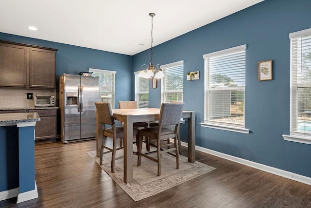 dining area with baseboards, a toaster, dark wood finished floors, and an inviting chandelier