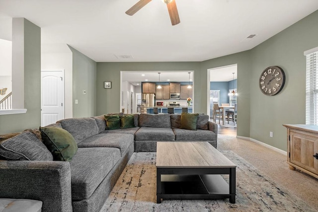 living room featuring light carpet, ceiling fan, visible vents, and baseboards