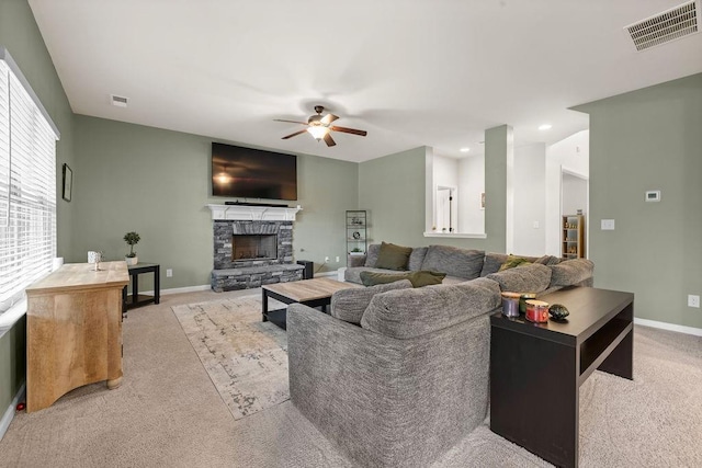 living area with ceiling fan, a stone fireplace, carpet, and visible vents