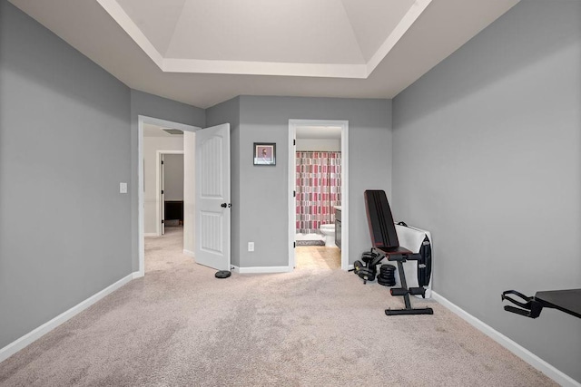 exercise area featuring lofted ceiling, carpet, baseboards, and a raised ceiling