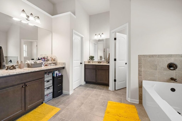 bathroom with two vanities, a sink, baseboards, and a bathing tub