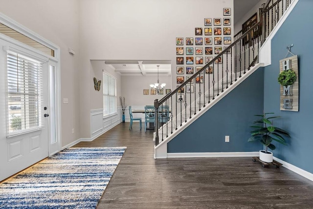 foyer with a chandelier, coffered ceiling, wood finished floors, baseboards, and stairway