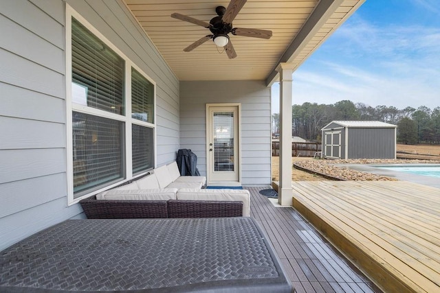 wooden deck with a storage shed, ceiling fan, an outdoor hangout area, and an outbuilding