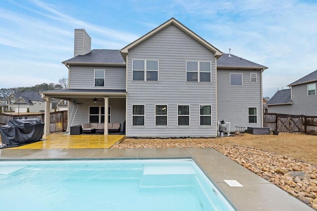 rear view of property featuring a fenced in pool, a chimney, ceiling fan, a fenced backyard, and an outdoor living space