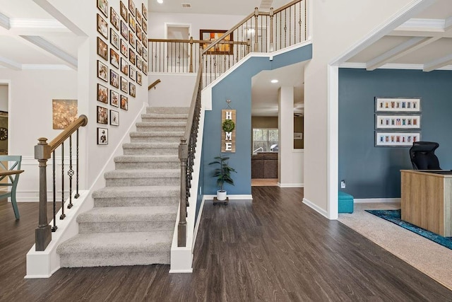 interior space with a high ceiling, beamed ceiling, wood finished floors, and baseboards