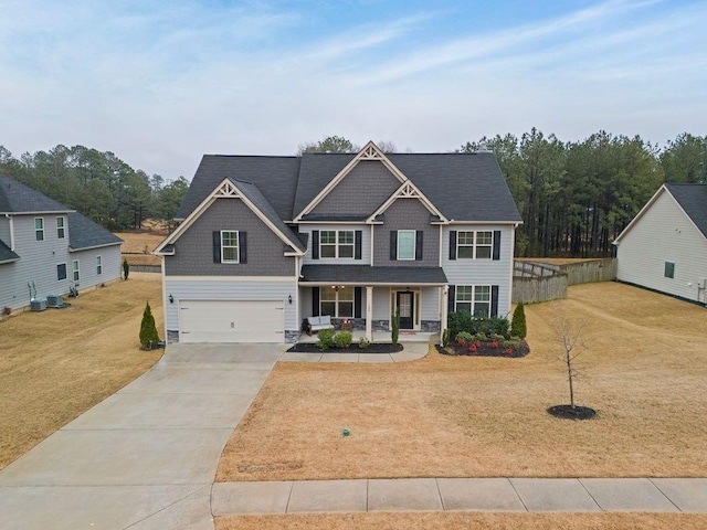 view of front of property featuring a garage, concrete driveway, a porch, and a front yard