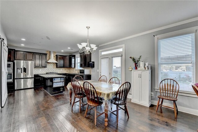 dining room with a barn door, crown molding, dark hardwood / wood-style floors, and a notable chandelier