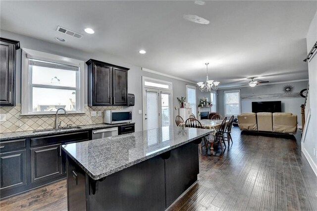 kitchen with a center island, sink, dark hardwood / wood-style floors, decorative light fixtures, and a breakfast bar