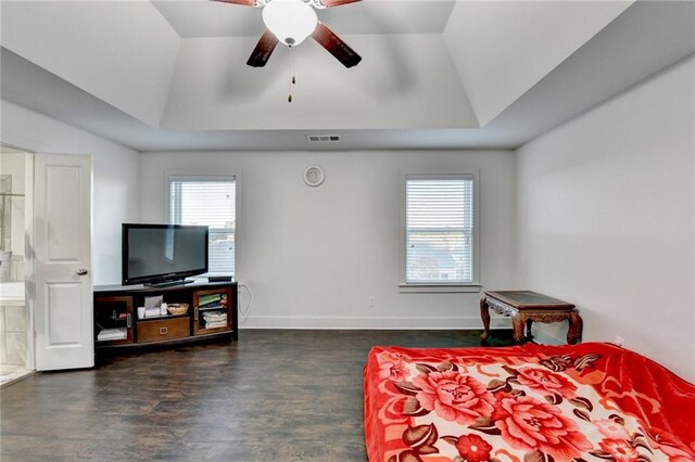 bedroom with a raised ceiling, vaulted ceiling, ceiling fan, dark hardwood / wood-style floors, and connected bathroom