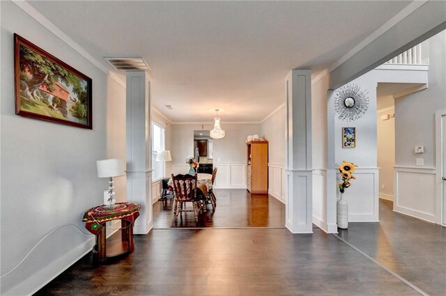 corridor featuring dark hardwood / wood-style flooring, ornate columns, and crown molding