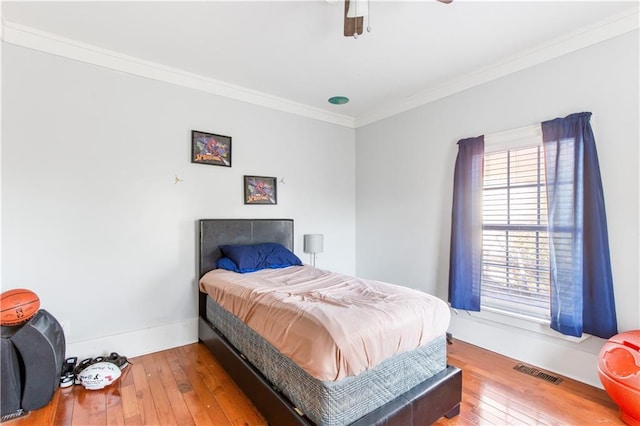 bedroom with ceiling fan, ornamental molding, and wood-type flooring