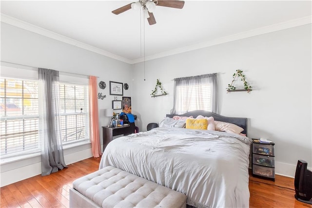 bedroom with ceiling fan, crown molding, hardwood / wood-style flooring, and multiple windows