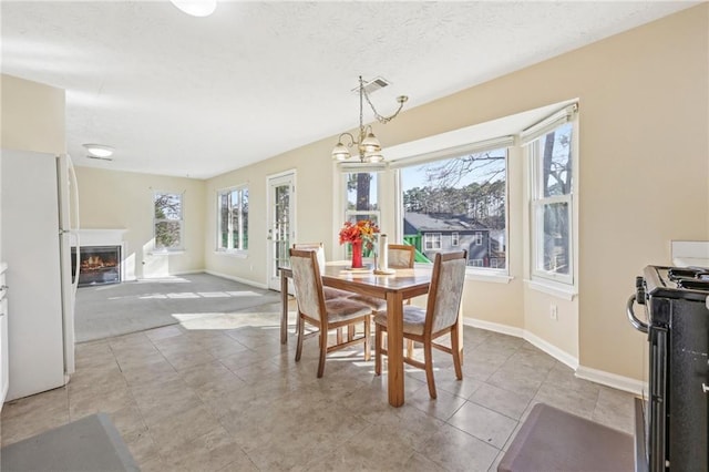1056 Shadow Lake Dr, Lithonia, GA 30058 - dining space featuring a warm lit fireplace, light tile patterned floors, a chandelier, and a textured ceiling