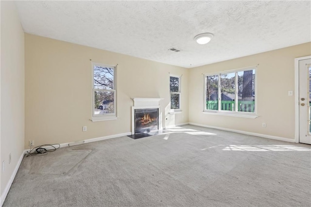 1056 Shadow Lake Dr, Lithonia, GA 30058 - unfurnished living room with carpet, healthy amount of natural light, a fireplace with flush hearth, and a textured ceiling