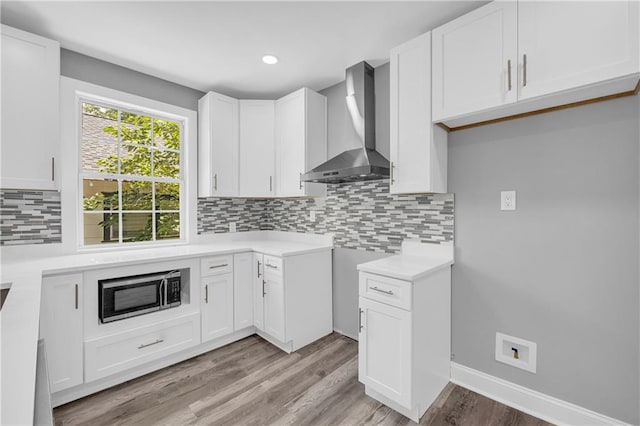 85 Ollie St, Atlanta, GA 30314 - kitchen with wall chimney exhaust hood, stainless steel microwave, light wood-type flooring, tasteful backsplash, and white cabinets