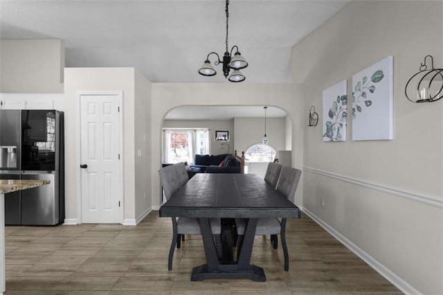 dining room featuring arched walkways, an inviting chandelier, and baseboards