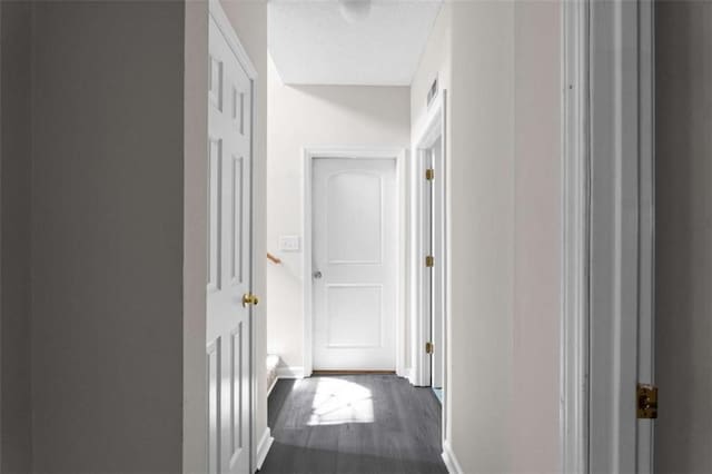 corridor with dark wood-style floors and baseboards