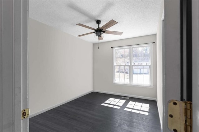 spare room featuring dark wood-style floors, a textured ceiling, and baseboards