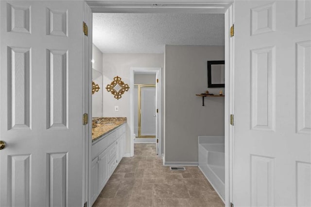 bathroom featuring a textured ceiling, a garden tub, visible vents, vanity, and a stall shower