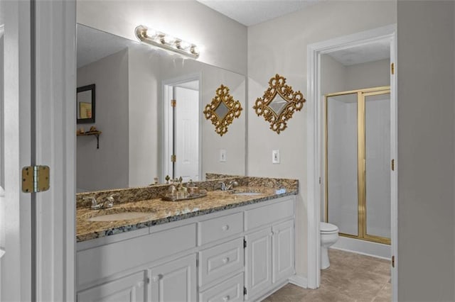 bathroom featuring a stall shower, a sink, toilet, and double vanity