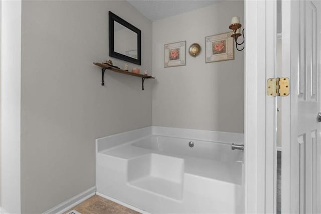 bathroom with a garden tub, baseboards, a textured ceiling, and tile patterned floors