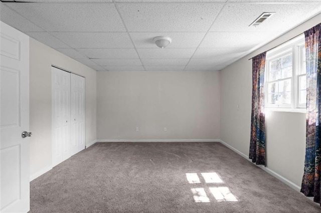 unfurnished bedroom featuring a paneled ceiling, carpet floors, visible vents, baseboards, and a closet