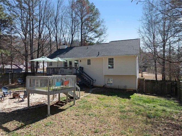 rear view of house featuring a yard, a chimney, a deck, a fenced backyard, and a fire pit