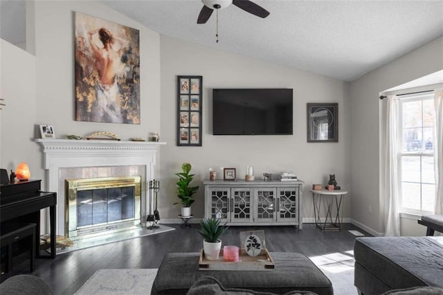 living room featuring a glass covered fireplace, vaulted ceiling, baseboards, and wood finished floors