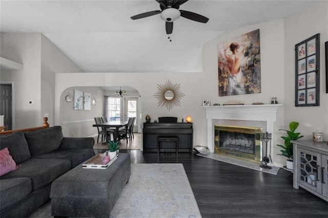 living room featuring arched walkways, a glass covered fireplace, lofted ceiling, ceiling fan, and wood finished floors