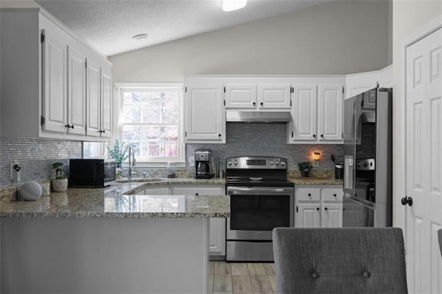 kitchen featuring a peninsula, electric range, white cabinetry, vaulted ceiling, and freestanding refrigerator