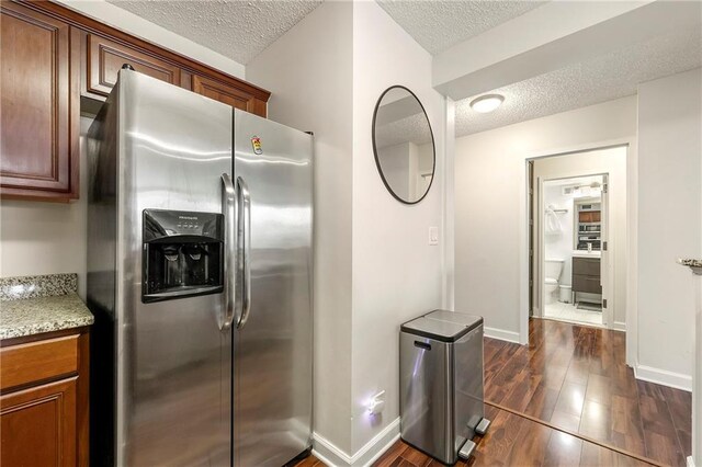 kitchen with stainless steel fridge, a textured ceiling, and dark hardwood / wood-style flooring