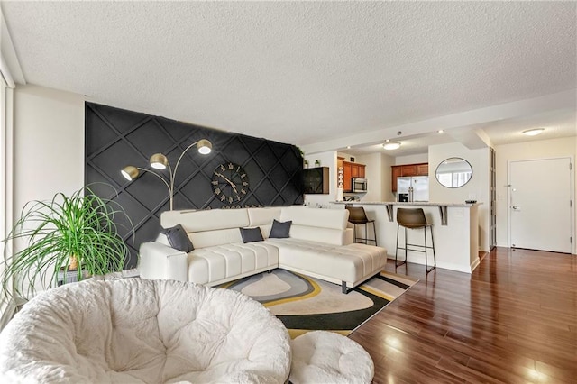 living room with a textured ceiling and dark hardwood / wood-style floors